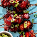 Air fryer chicken skewers with green onions on top.