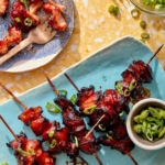 Air fryer chicken skewers on a platter with green onions.