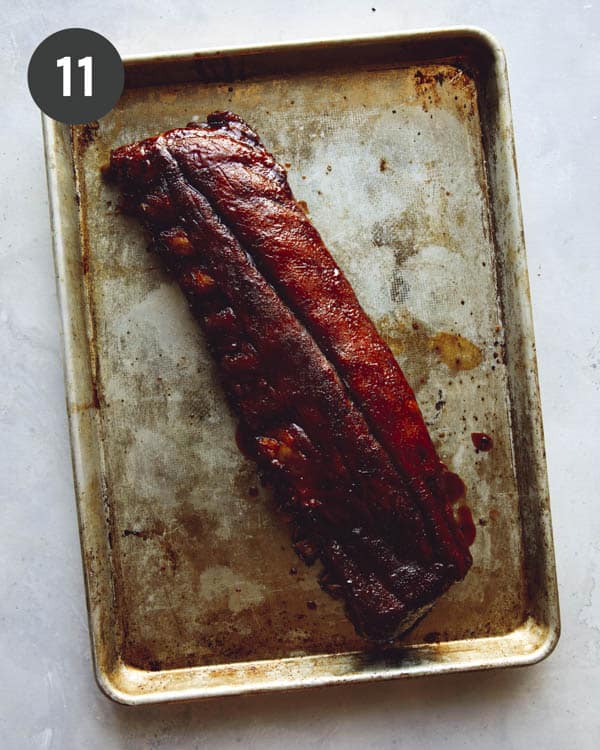 Sticky oven baked ribs on a a baking sheet ready to be cut up.