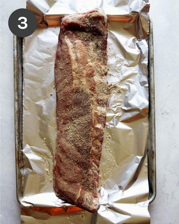 Ribs rubbed with spice on baking sheet with tin foil.
