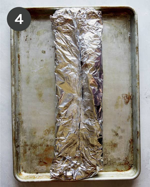 Ribs wrapped in tin foil on a baking sheet to make oven baked ribs.