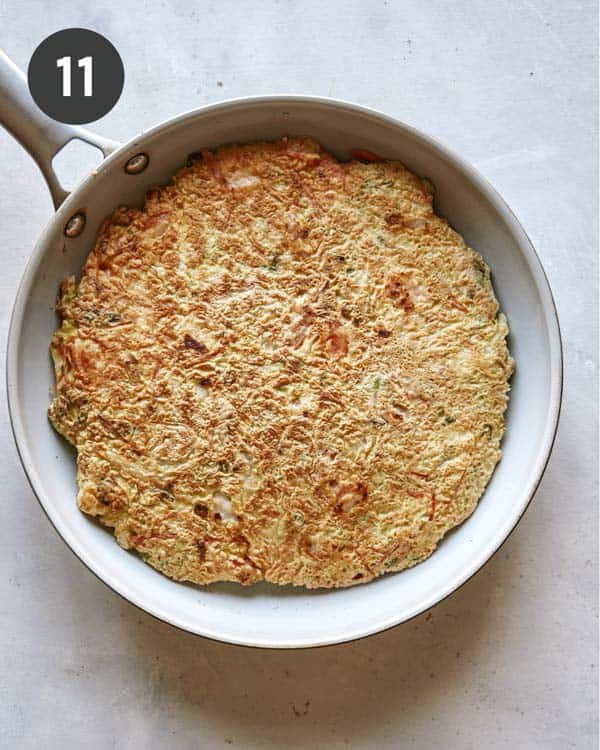 Okonomiyaki cooking in a skillet.