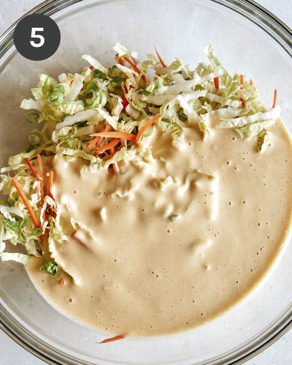 Mixing vegetables and batter in a glass bowl.