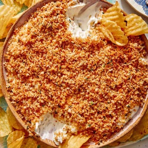 Fried pickle dip in a bowl with potato chips on the side.