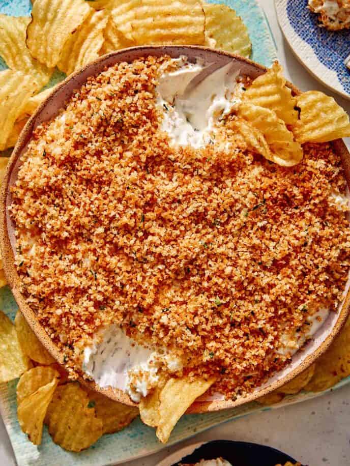 Fried pickle dip in a bowl with potato chips on the side.