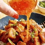 Sweet chili sauce being poured onto crispy tofu.