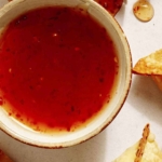 Sweet chili sauce next to some air fryer crab rangoon.