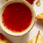 Sweet chili sauce next to some air fryer crab rangoon.