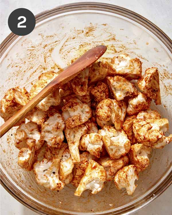 Oil and seasonings mixed together with cauliflower.