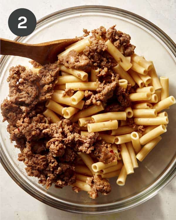 Meat mixed with pasta in a bowl for baked ziti. 