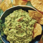 Guacamole recipe in a bowl with chips on the side.