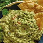 Guacamole up close in a bowl with chips in it.