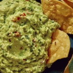 Guacamole up close in a bowl with chips in it.