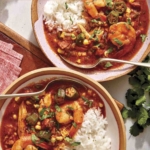 Two bowls of gumbo with cilantro on the side.