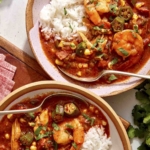 Two bowls of gumbo with cilantro on the side.