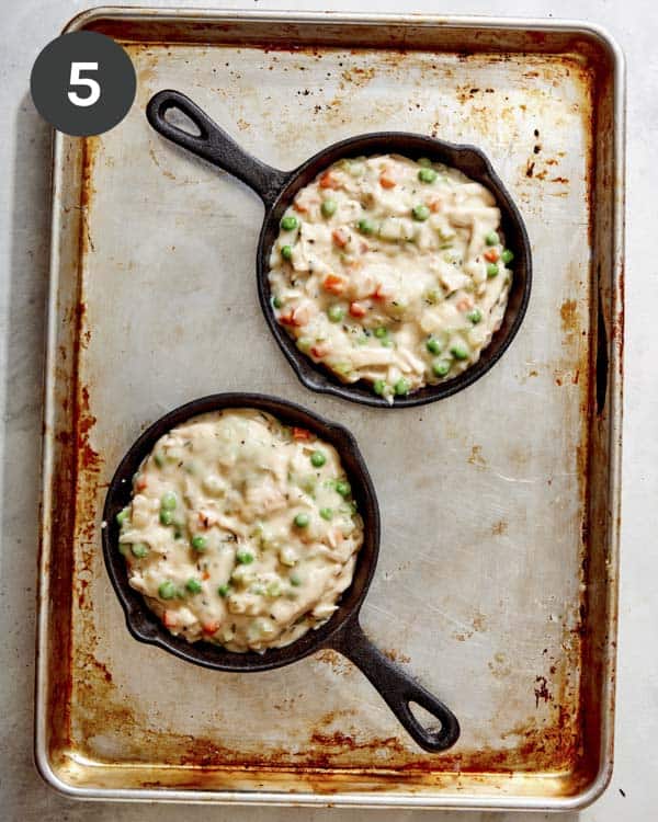 Chicken pot pie on a sheet pan in individual skillets. 