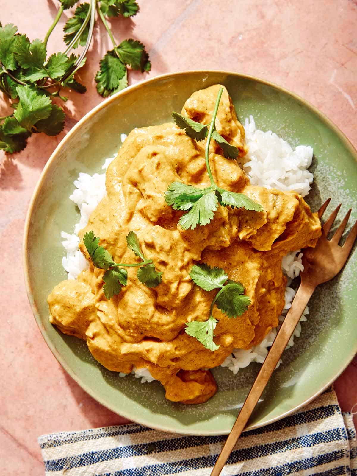 Chicken korma on a plate with rice and a fork.