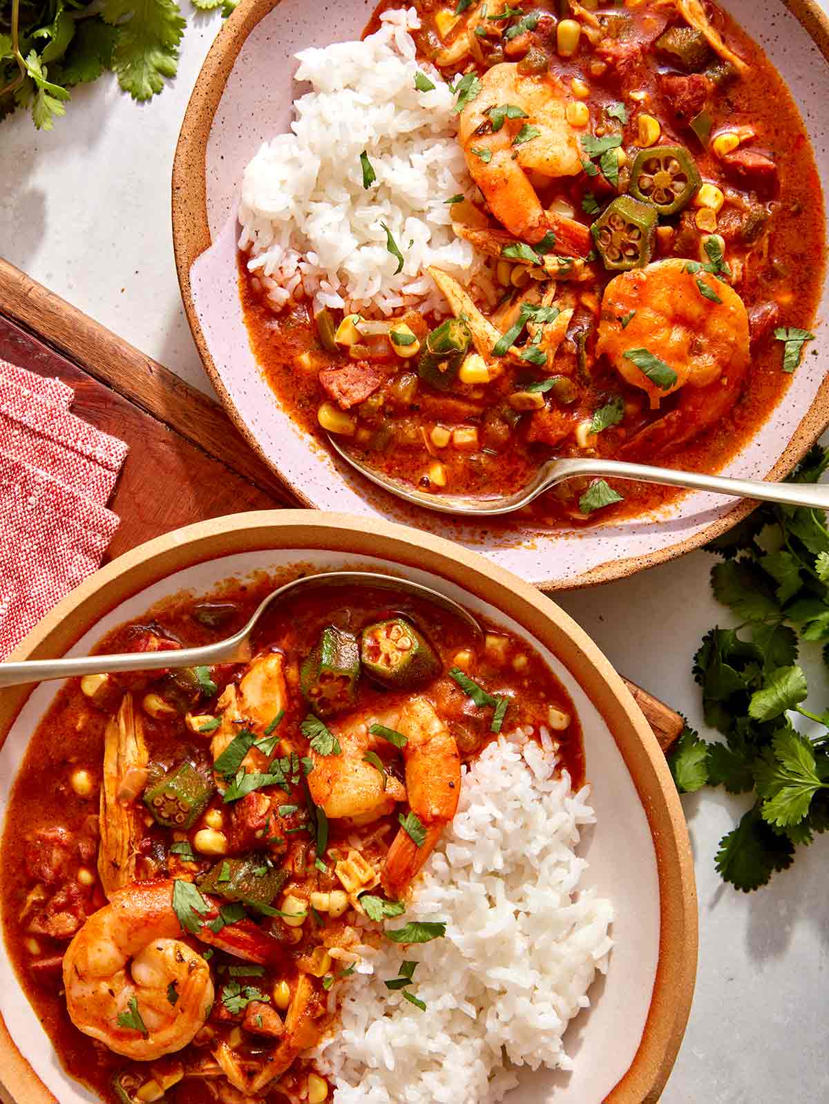 Two bowls of gumbo with cilantro on the side. 