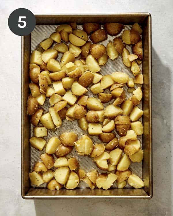 Potatoes in a baking sheet about to be roasted.