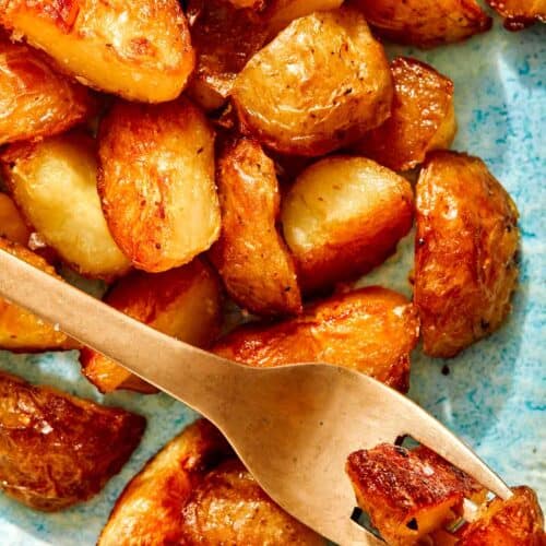 Crispy roasted potatoes on a platter with a fork.