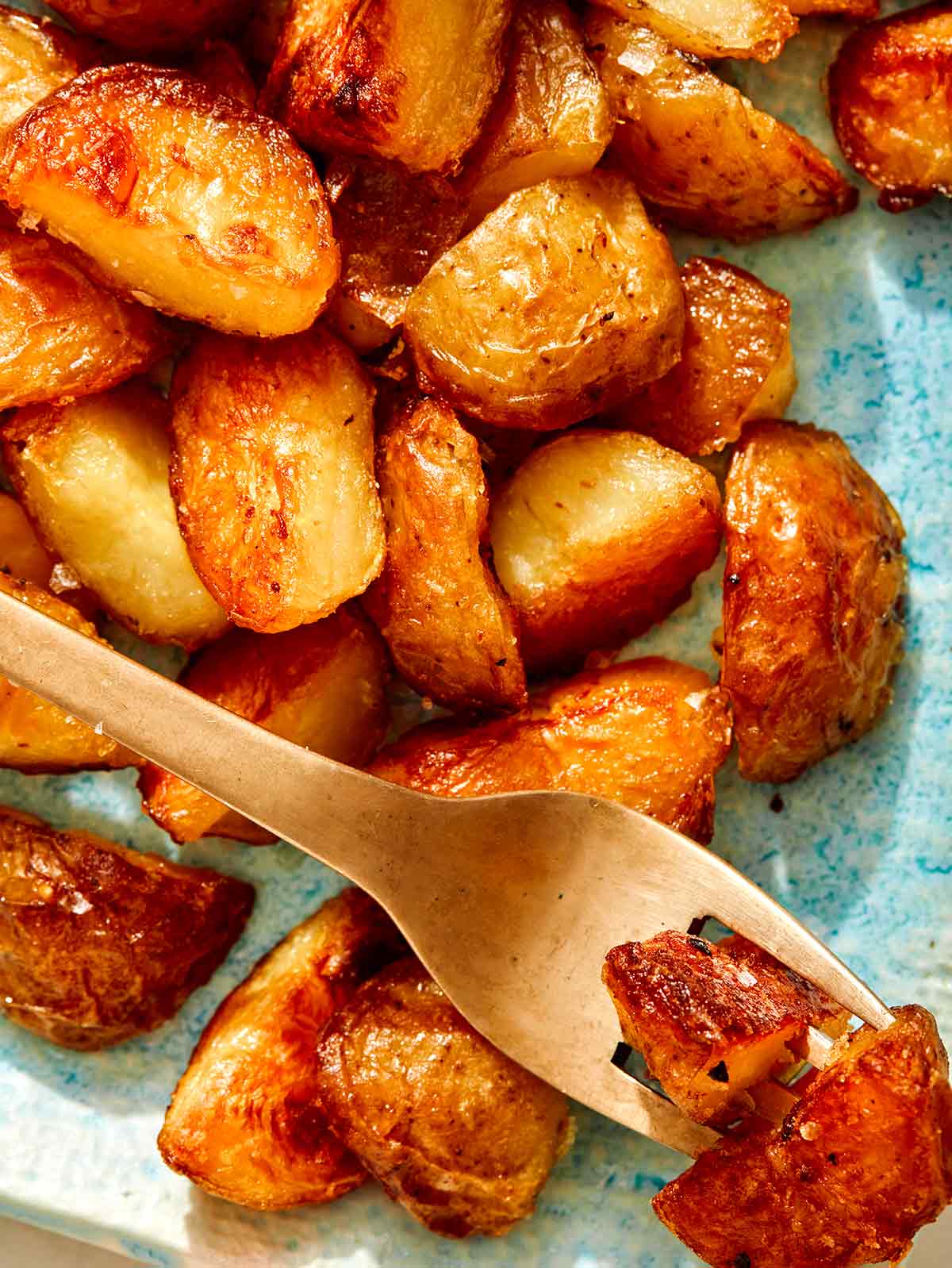 Crispy roasted potatoes on a platter with a fork. 