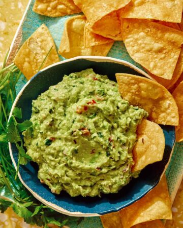Guacamole recipe in a bowl with chips on the side.
