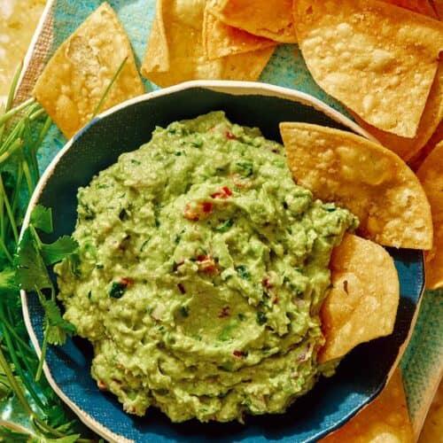Guacamole recipe in a bowl with chips on the side.