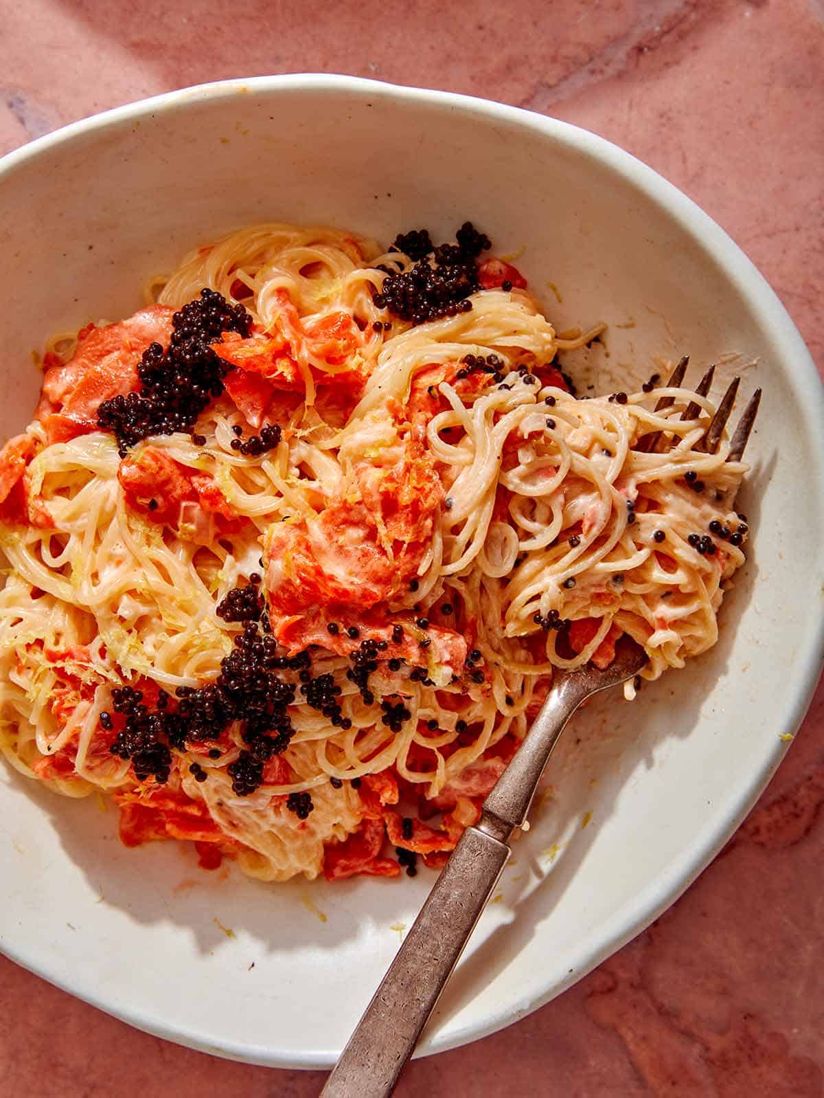 Close up on a bowl of smoked salmon pasta with a fork. 