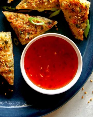 Sweet chili sauce in a ramekin next to shrimp toast.
