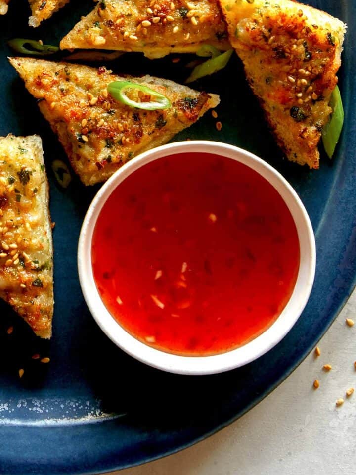 Sweet chili sauce in a ramekin next to shrimp toast.