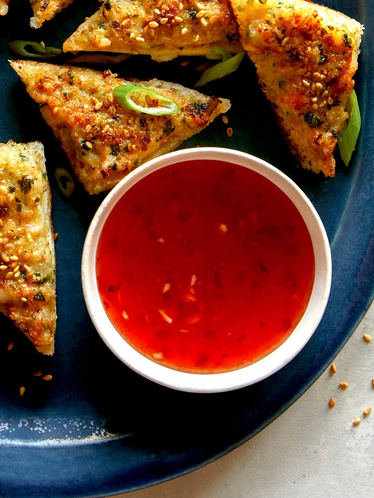 Sweet chili sauce in a ramekin next to shrimp toast. 