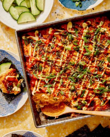 Salmon sushi bake in a baking dish with cucumbers and nori.