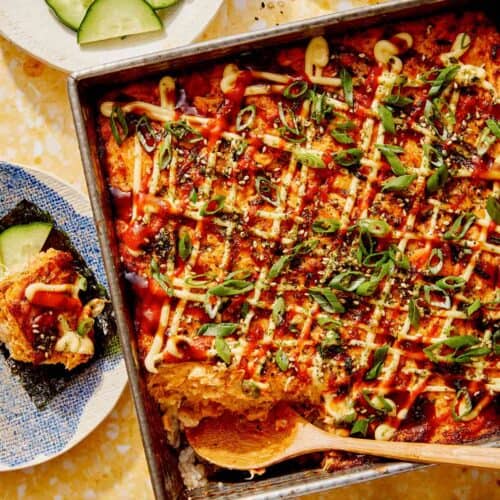 Salmon sushi bake in a baking dish with cucumbers and nori.