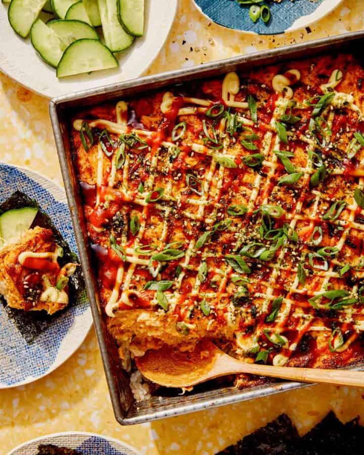 Salmon sushi bake in a baking dish with cucumbers and nori.