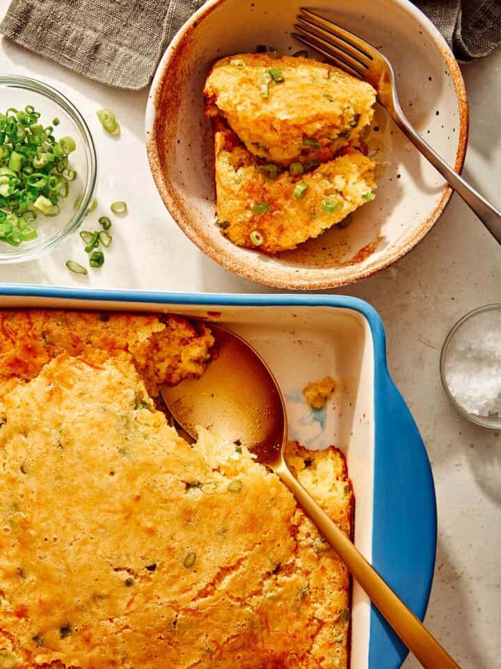 Jalapeno cheddar spoon bread in a baking dish with some served into a bowl.