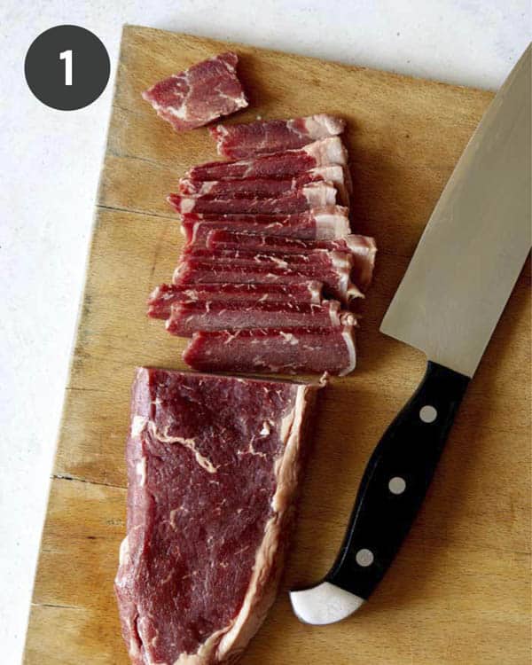 Slicing strip steak on a cutting board for Mongolian Beef.