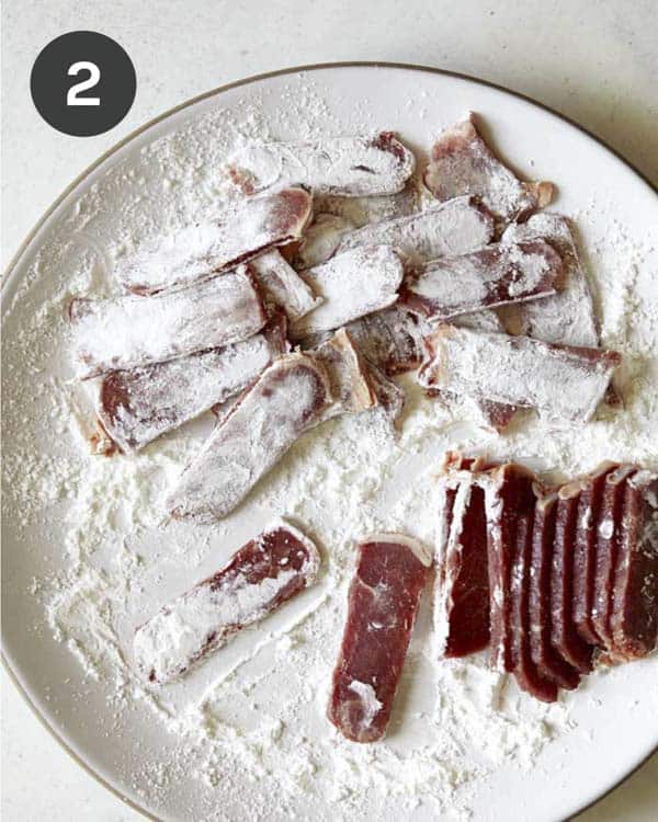 Tossing seasoned strip steak in cornstarch to make Mongolian Beef.