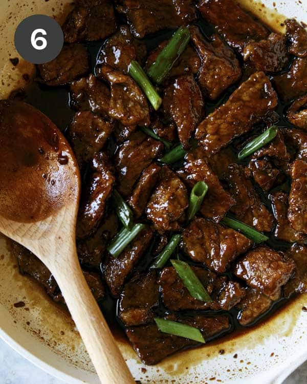 Mongolian beef in a skillet with green onions. 