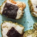 Close up on spicy tuna onigiri with one dipped in masaga sauce.