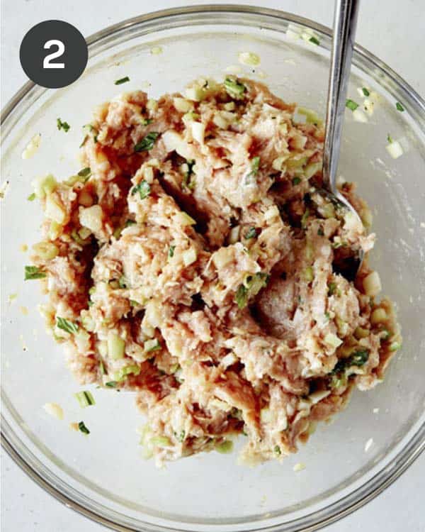 Potsticker filling ingredients in a glass bowl mixed together. 