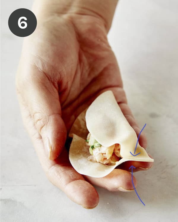 Pinching the end of a wonton wrapper to make a potsticker. 