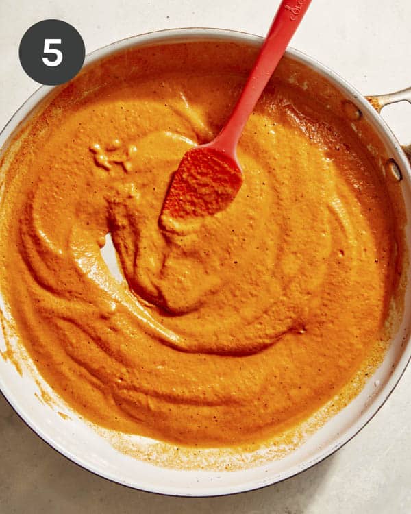 Romesco sauce pasta in a skillet simmering. 