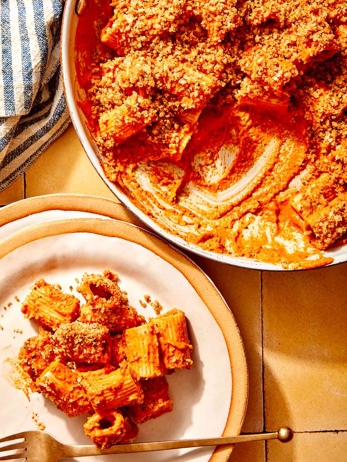 Romesco sauce pasta being served onto a plate with a fork. 