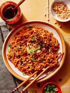 Spicy ramen noodles in a bowl with peanuts and green onions on top.