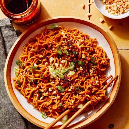 Spicy ramen noodles in a bowl with peanuts and green onions on top.