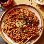 Spicy ramen noodles in a bowl with peanuts and green onions on top.