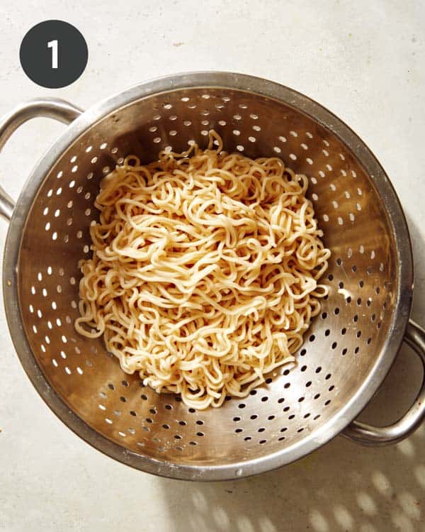 Cooked ramen noodles in a colander.