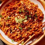 Spicy ramen noodles in a bowl with peanuts and green onions on top.