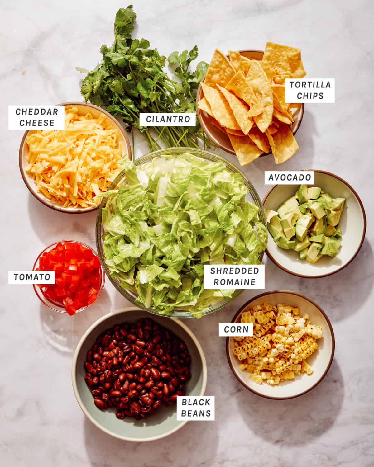 Taco salad ingredients in bowls.
