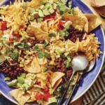 Taco salad in a big bowl with a plate on the side.